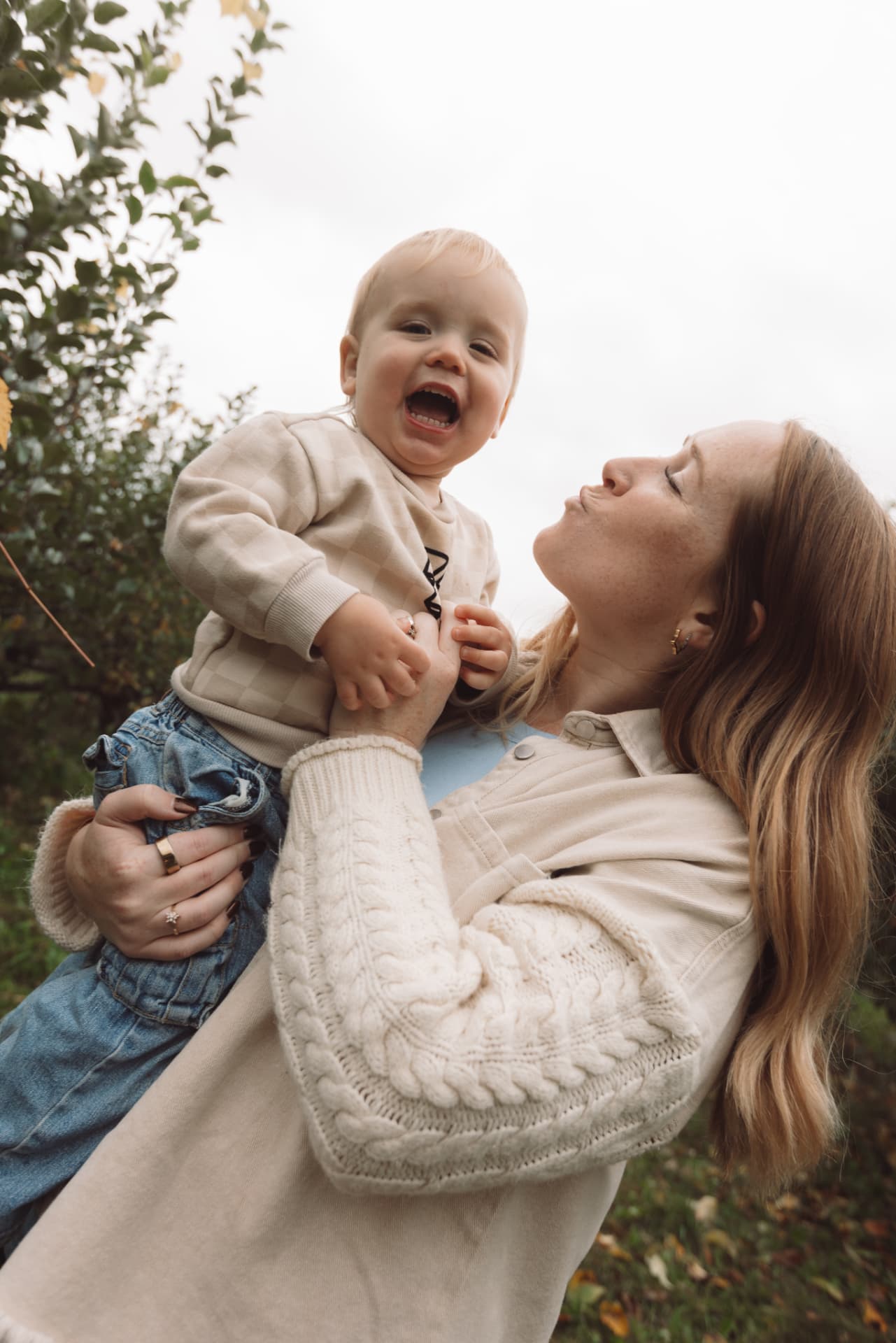 Marisa holding her smiling toddler in an apple orchard